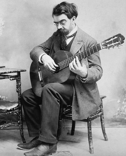 Tarrega sitting and holding a guitar