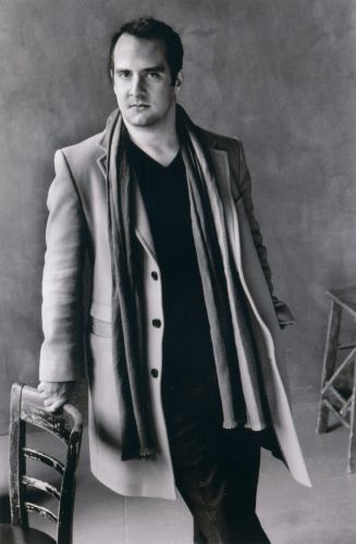 Black and white photo of Tarik O'Regan leaning on a chair